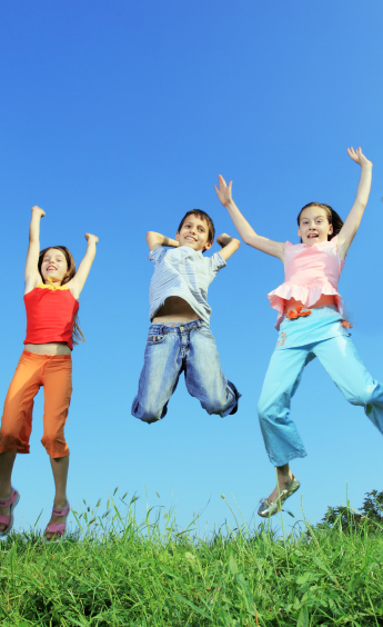 Group of five happy children jumping outdoors.